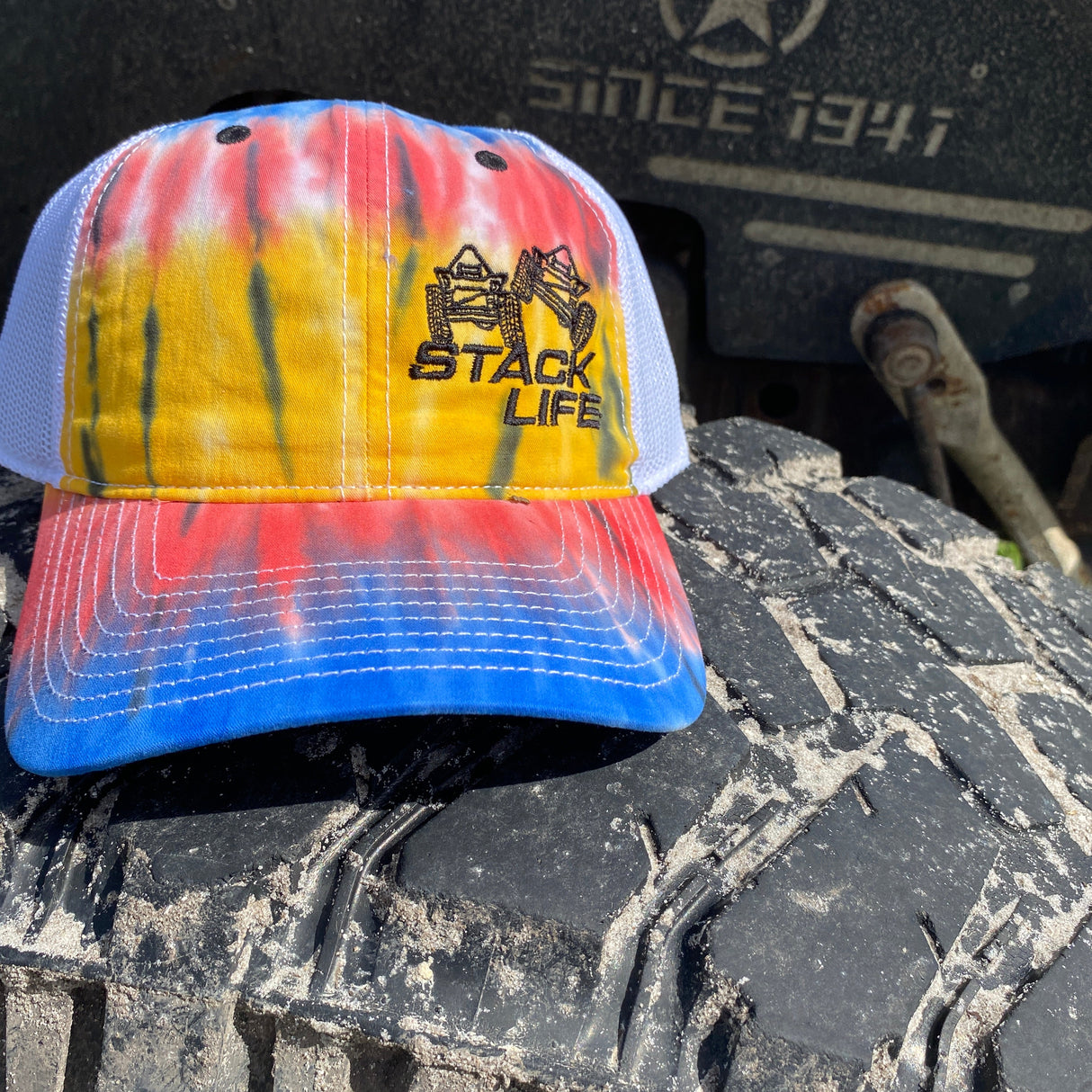 red tie dyed stack life trucker hat with black logo