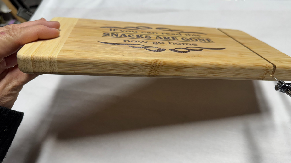 side view of bamboo cutting board with if you can read this snacks are gone now go home engraved on the top