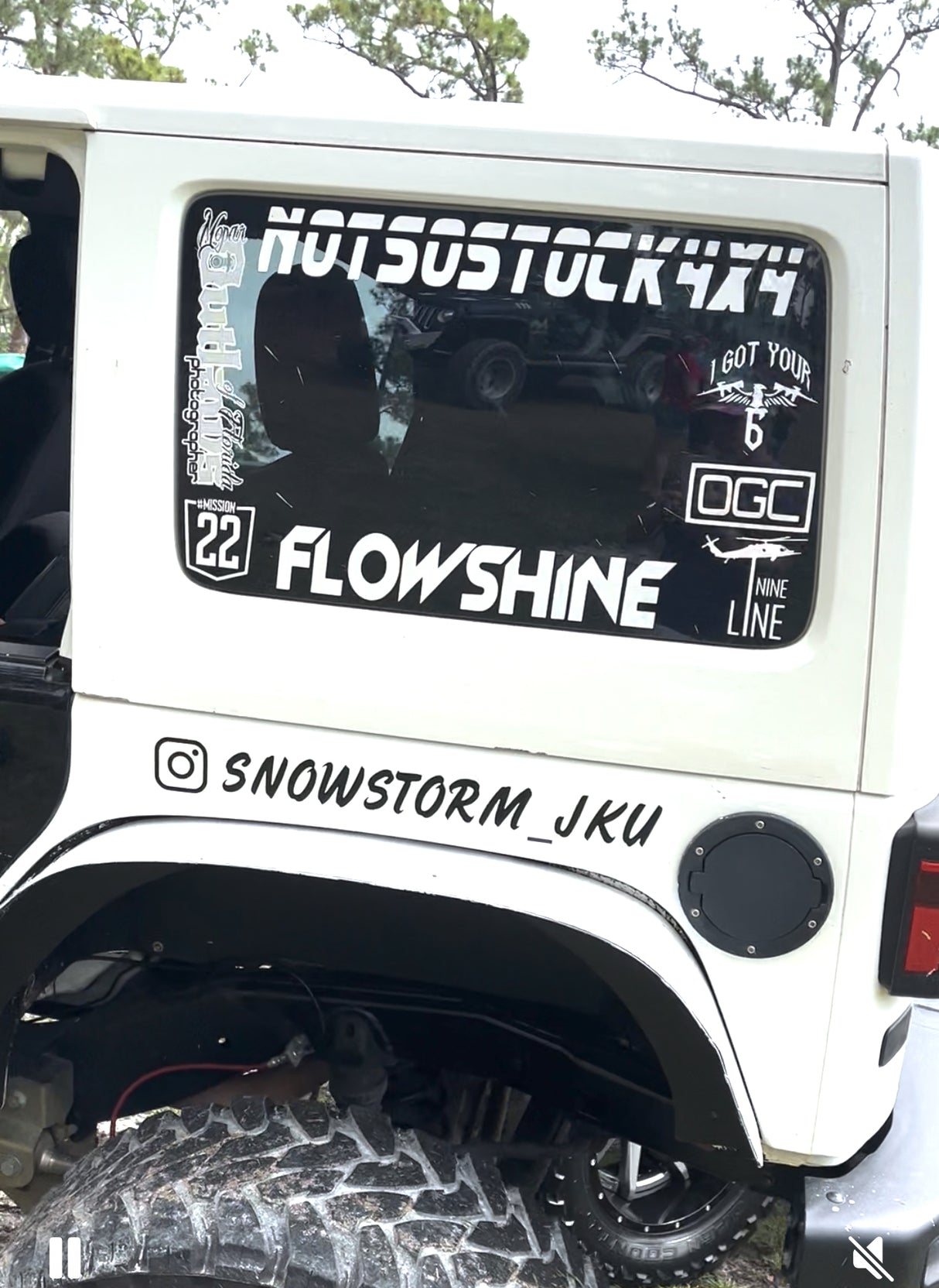 White vehicle with various decals and stickers on the window and rear.