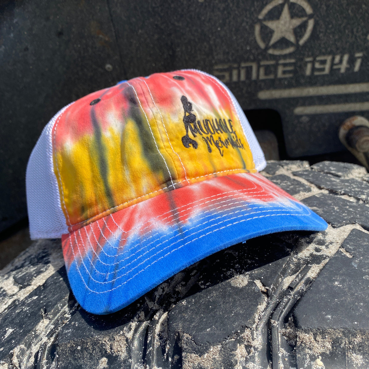 red black and blue tie dyed trucker hat with black mudhole mermaid logo