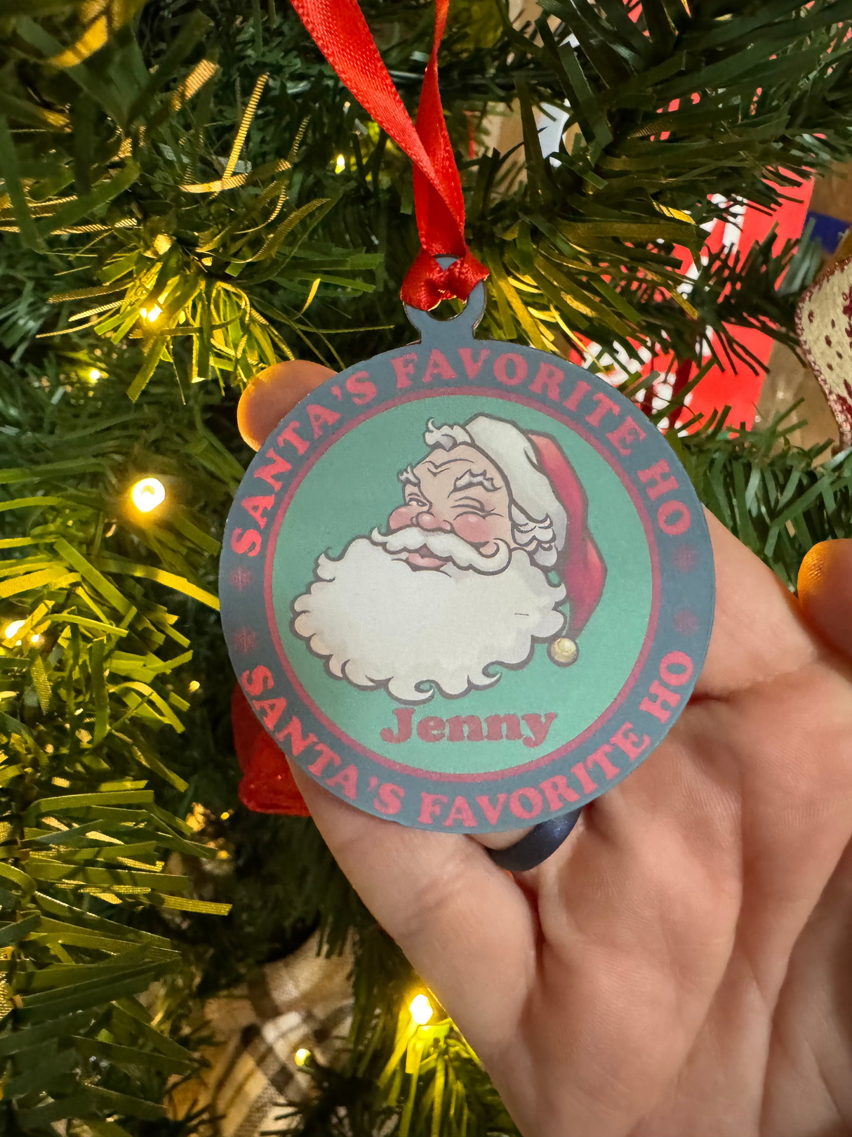 Vintage-style acrylic Christmas ornament featuring a winking Santa, the text "Santa's Favorite Ho," and a customizable name in festive colors, hanging on a tree.