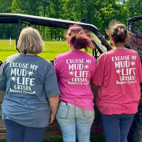 3 ladies with Excuse My mudlife crisis shirts on in pink, grey and red