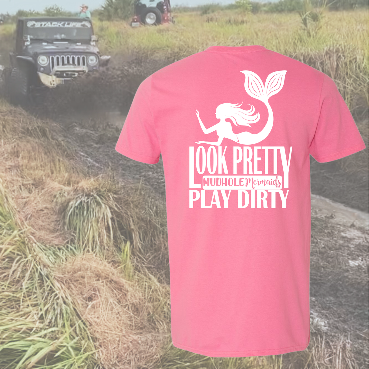 Pink t-shirt with Look Pretty Play Dirty mermaid graphic and text in a muddy field with off-road vehicle.