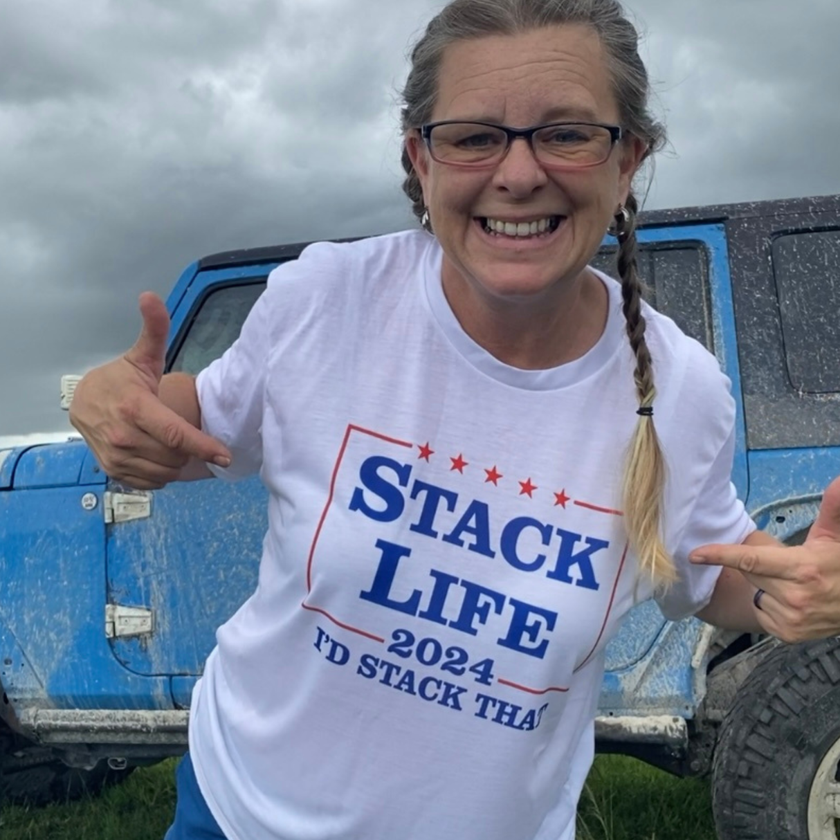Person wearing a 'Stack Life 2024' t-shirt in front of a blue truck.