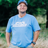 Man wearing a blue 'Stack Life' t-shirt and cap outdoors